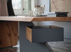 a wooden desk with drawers and a vase on the table in front of it next to a window