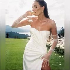 a woman in a white dress holding a wine glass with her right hand on her hip