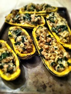 stuffed squash with stuffing and spinach on a baking sheet ready to be cooked in the oven