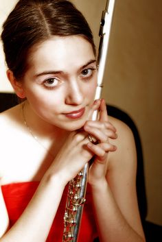 a woman in a red dress holds an umbrella over her head and looks at the camera