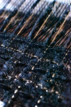 closeup of woven material with water drops on it, including black and gold threads