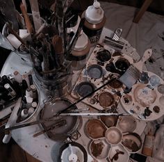 an artist's palettes and brushes on a table covered in dirty paint pots