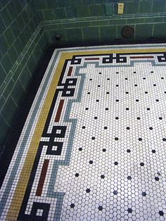 a tiled floor in a bathroom with green tiles and yellow trimmings on it