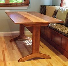 a wooden table sitting on top of a hard wood floor next to a couch and window