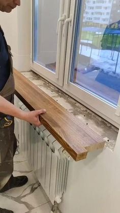 a man standing in front of a window with a wooden board on it's side