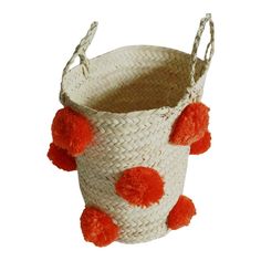 a white basket with orange pom - poms hanging from the handles and sides