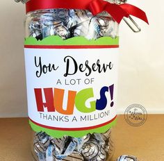 a jar filled with lots of hugs on top of a table next to a pile of candy