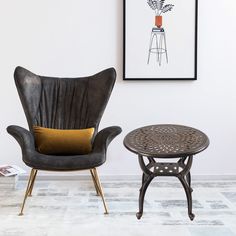 two chairs and a table in a room with a framed plant on the wall behind them