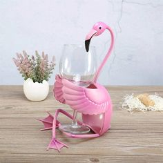 a pink flamingo wine glass holder sitting on top of a wooden table