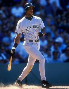 a baseball player holding a bat while standing on top of a field in front of a crowd