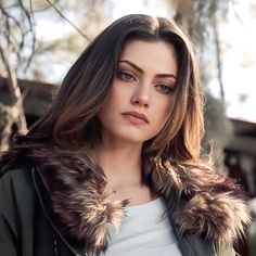 a woman with long hair wearing a jacket and fur collar, looking at the camera