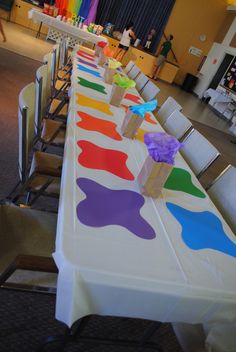 a long table is decorated with colorful cupcakes and paper napkins on it