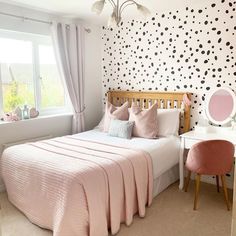 a bedroom decorated in pink and black with polka dots on the wall behind the bed