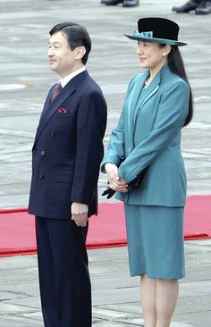 two people standing next to each other wearing suits and hats