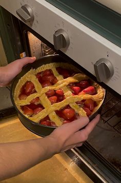 a person taking a pie out of an oven