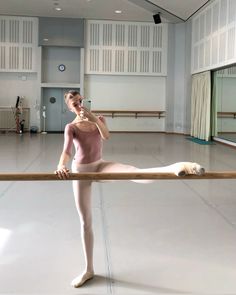 a ballerina is standing on one leg and holding the bar in her hand while she's wearing a pink leotard