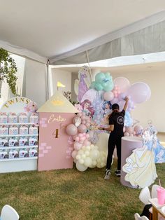 a person standing in front of a pink castle with balloons and princess decorations on it