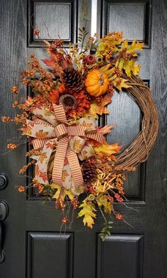 a wreath with fall leaves and pine cones on the front door is ready to be hung