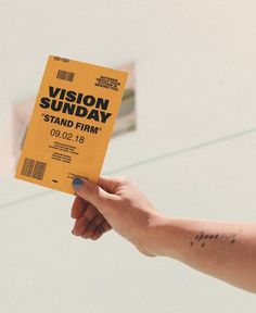 a person holding up a yellow book with the words vision sunday on it in front of a building