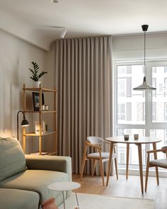 a living room filled with furniture and a dining table next to a window covered in curtains