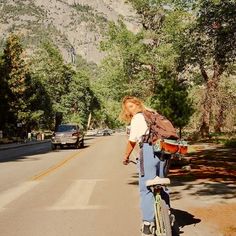 a person riding a bike on the side of a road with mountains in the background