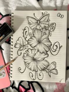 a notebook with flowers and butterflies on it next to a pink phone, pen and marker