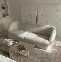 a living room with a couch and coffee table in the middle, white carpet on the floor