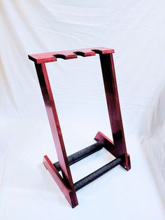 a wooden stand with two black handles on it's sides and one red frame in the middle