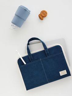 a blue bag sitting on top of a white table next to a cup and cookie