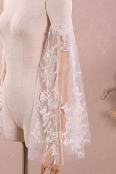 a mannequin is wearing a white dress with sheer sleeves and flowers on it