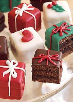 there are many different types of cakes on the glass platter with red, green and white icing