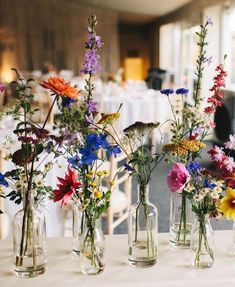 several vases filled with different types of flowers on a table at a wedding reception