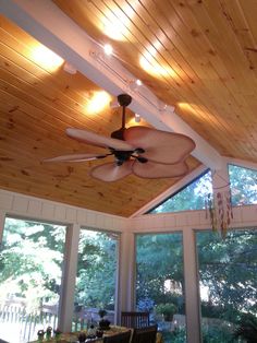 a ceiling fan is hanging from the ceiling in a room with wood paneling and large windows