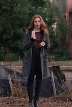 a woman standing in the dirt holding a book