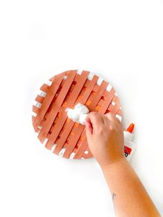 a person is painting an orange piece of brick with white paint on the top and bottom