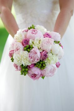 a bride holding a bouquet of pink and white flowers