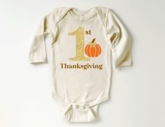 Celebrate baby's first Thanksgiving in shimmering style with our "1st Thanksgiving Sparkly Gold" Natural Bodysuit, a memorable addition to their holiday wardrobe. Special First Thanksgiving Design: Featuring a sparkling "1st Thanksgiving" in gold script, adding a touch of elegance to your little one's holiday attire. Soft and Comfortable: Crafted from soft cotton fabric, ensuring gentle comfort and breathability for your baby's delicate skin during festive celebrations. Practical and Stylish: Sh Babys First Thanksgiving, Wedding Bottle Labels, Summer Cups, Bachelorette Tees, Birthday Wine Glasses, Christmas Baby Announcement, Christmas Wine Glasses, Big Sister Little Sister, Grandpa Funny