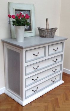 a white dresser with flowers and a basket on top