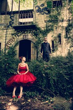 a man and woman standing in front of an old building with ivy growing on it