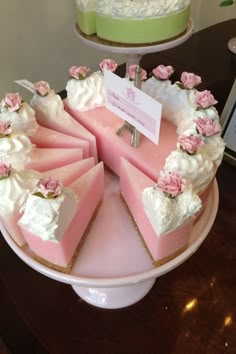 there is a pink cake with white frosting and flowers on the top, sitting on a plate