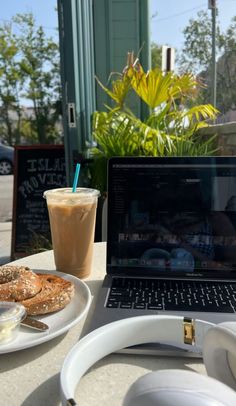 an open laptop computer sitting on top of a table next to a plate of food