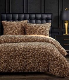 a leopard print comforter set on a bed in a room with black walls and wooden flooring