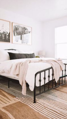 a bedroom with a bed, rug and pictures on the wall