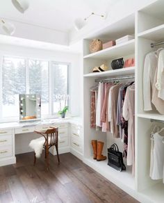 a white closet filled with lots of clothes next to a desk and chair in front of a window