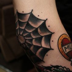 a spider web tattoo on the arm with an orange and black heart in it's center