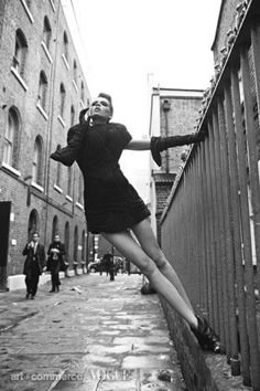 a woman leaning against a wall in an alley