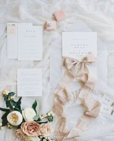 the wedding stationery is laid out on top of the bed with flowers and ribbons