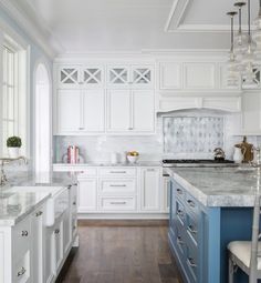 a large kitchen with white cabinets and blue counter tops, along with an island in the middle