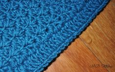 a blue crocheted blanket laying on top of a wooden floor