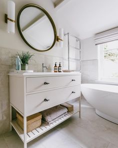 a bathroom with a sink, mirror and bathtub next to a window in it